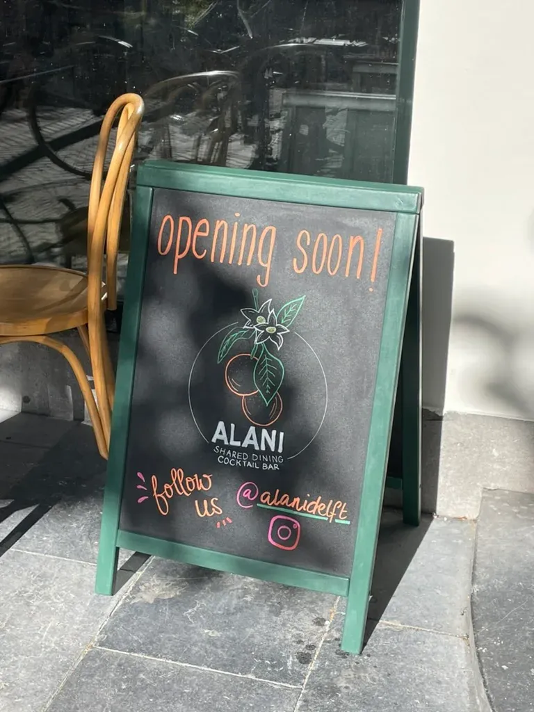 A green chalkboard outside the restaurant announcing "opening soon" with the Alani logo.