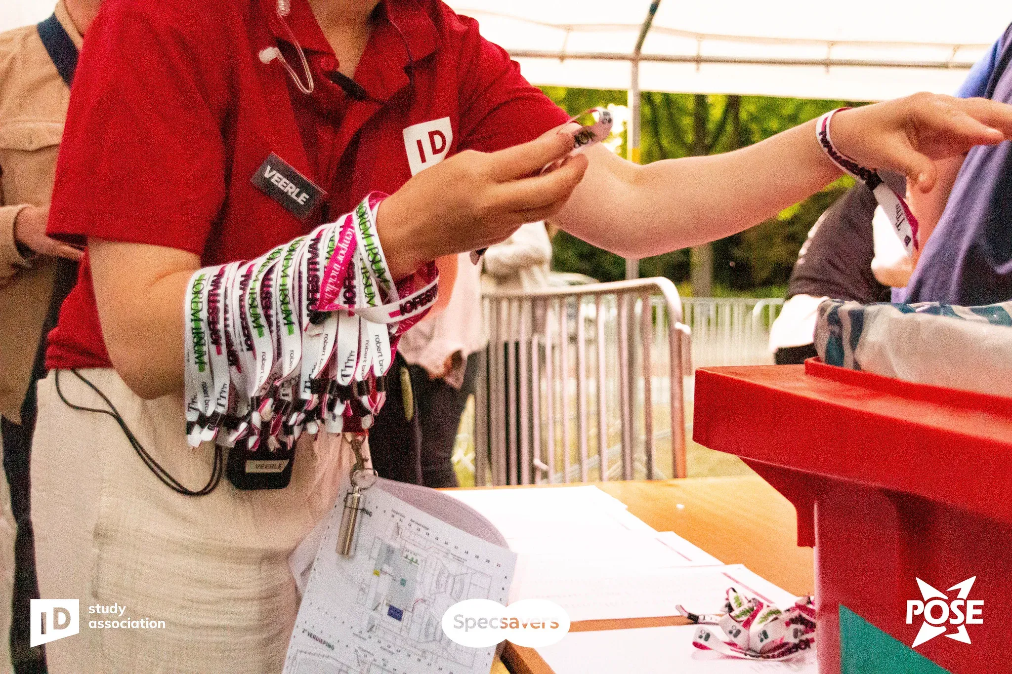 A crew member at the entrance holding a bundle of wristbands, ready to hand them out.