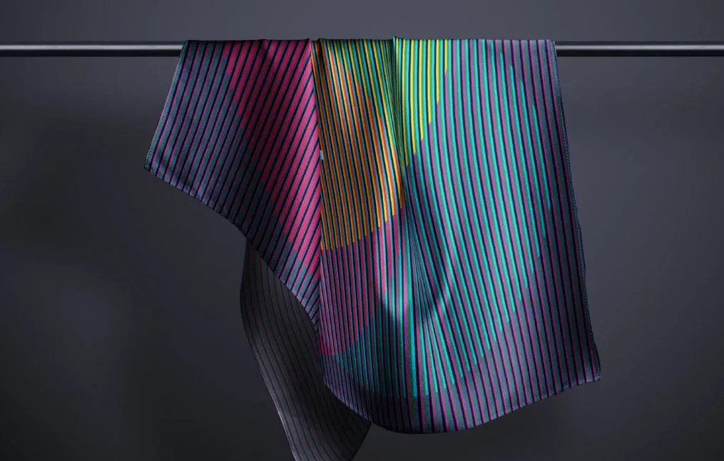 A scarf hanging over a rail, printed with the striped event pattern in purple, pink, green and blue.