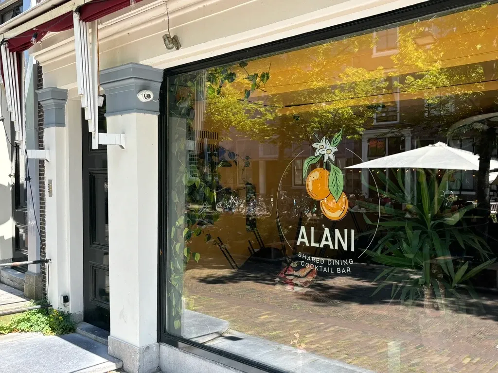 The Alani shop window in Delft, with the orange branch logo applied to the glass.